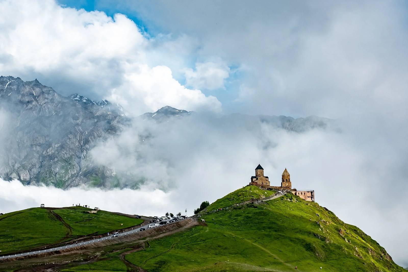 Gergeti Trinity Church on the ridge below Mount Kazbek, Georgia, with cloud banked against the range behind it.